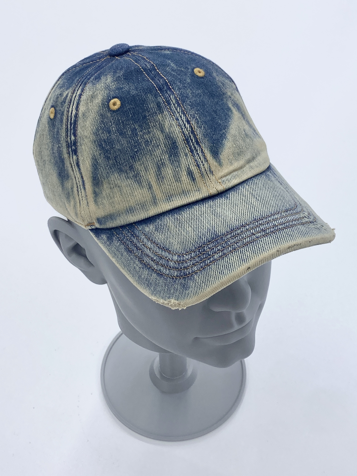 Decorated denim cap sample on a display stand